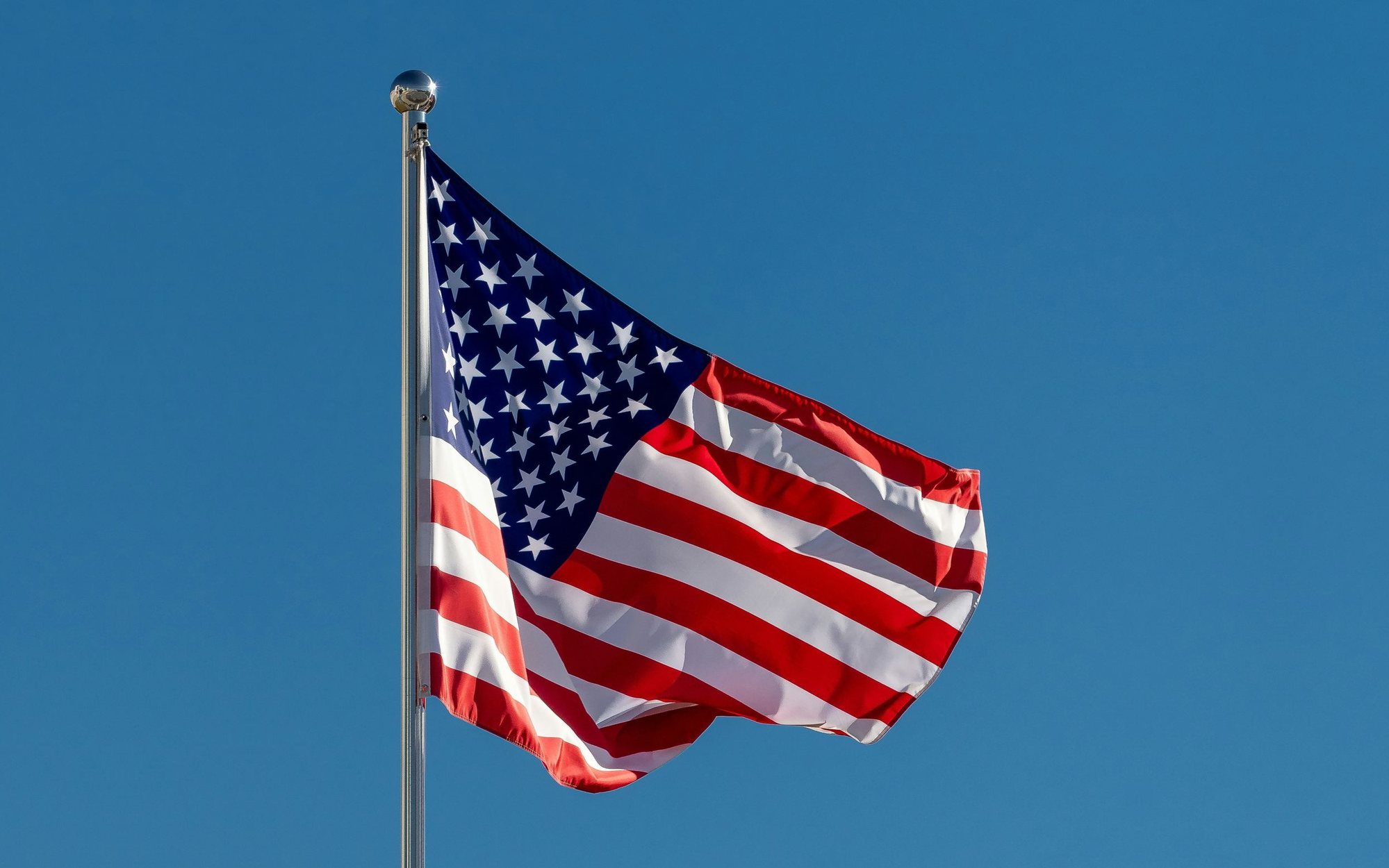 American flag on a commercial flagpole against a clear blue sky