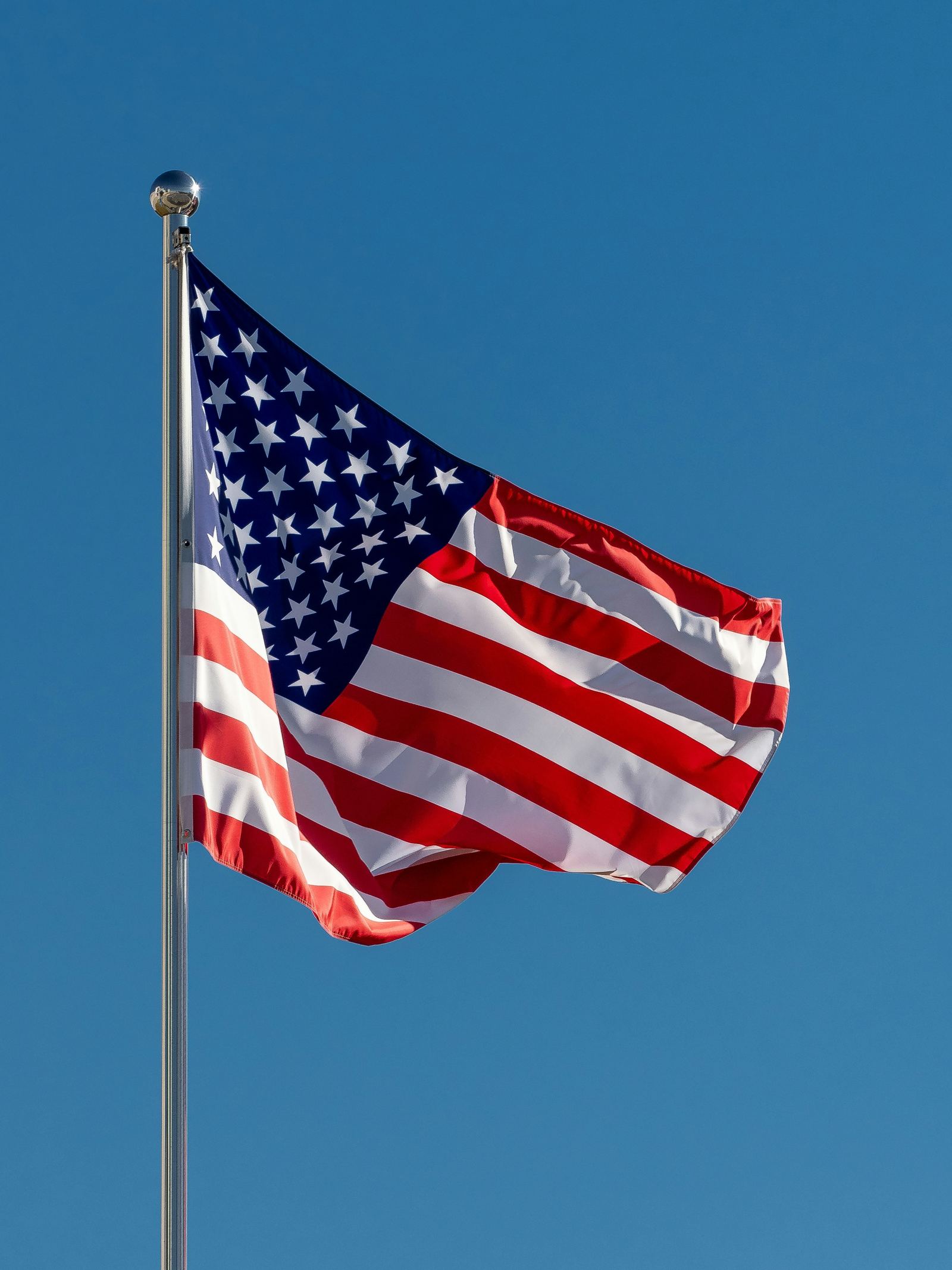 American flag on a commercial flagpole against a clear blue sky
