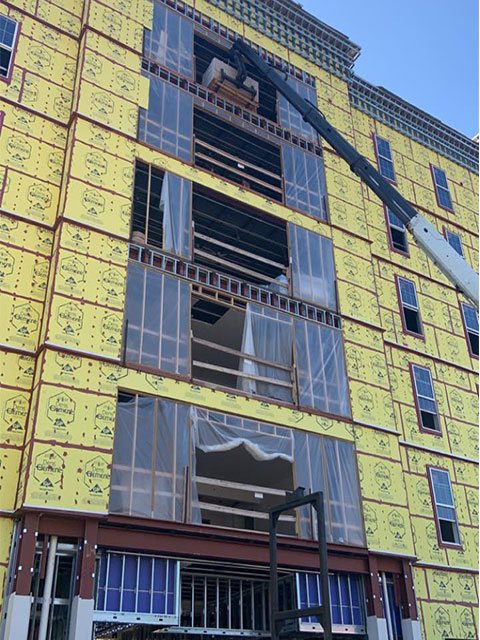 Multi-story commercial building under construction with framed storefront openings and a crane