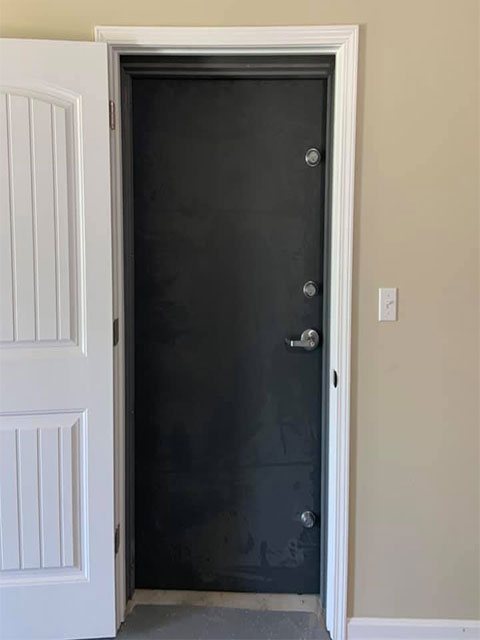 Dark steel security door with a lever handle and multiple locking points installed in a home