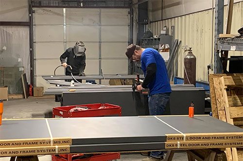 Bluegrass team members welding and fabricating steel doors inside the shop